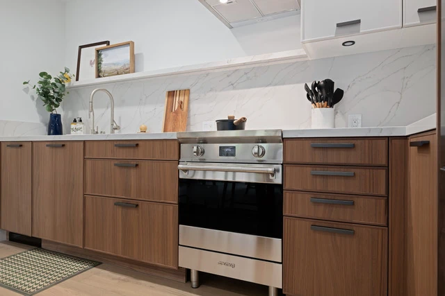Walnut Skinny Shaker base cabinets, full-height calacatta backsplash, Smeg slide-in range, white slab uppers