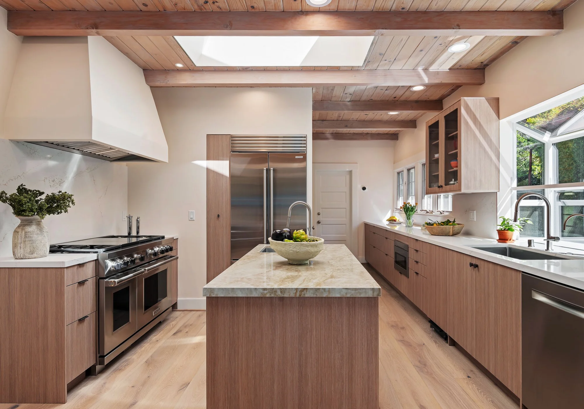Range wall with paneled Sub-Zero column, full-height stone backsplash, and Linear oak cabinetry