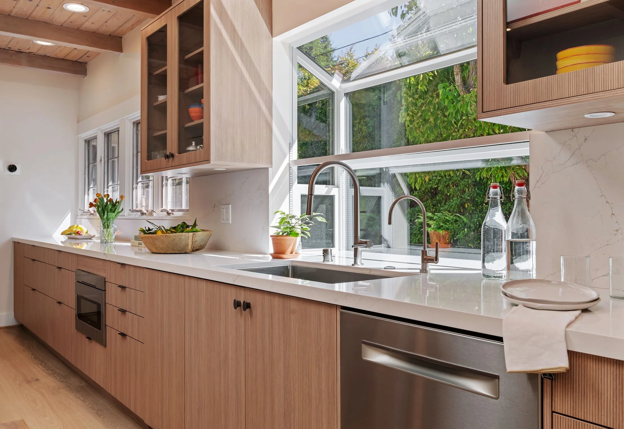Sink detail with bridge faucet and water filter, garden window framed behind